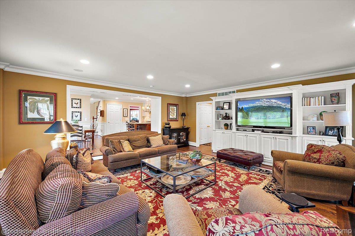 135 Clifton Road Bloomfield Hills, MI 48301 - Photo 28 of 77 Spacious living area featuring recessed lighting, crown molding, wood-finish flooring, and a built-in entertainment center with shelving and storage