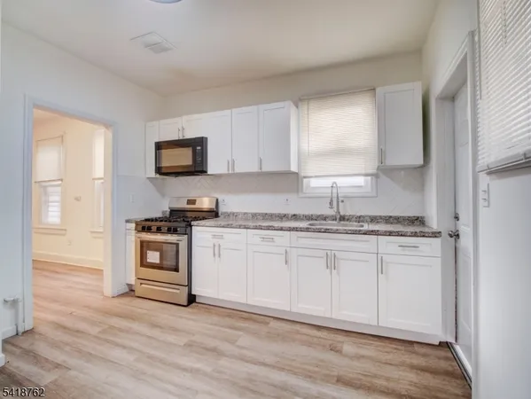 a kitchen with granite countertop a stove a sink and a microwave