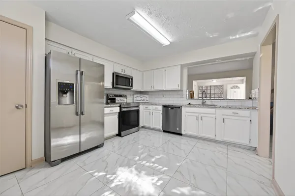 a kitchen with white cabinets stainless steel appliances and a window
