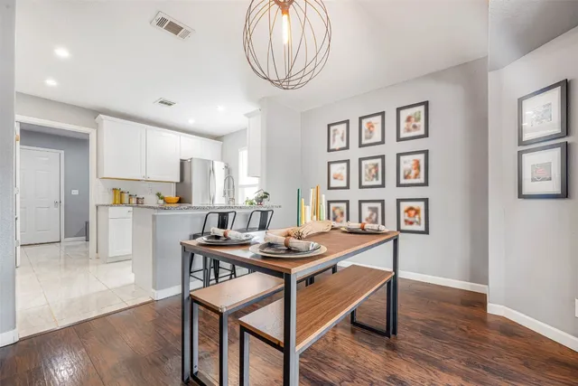 a room with stainless steel appliances a table chairs and a refrigerator