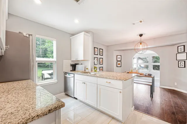 a kitchen that has a lot of white cabinets and wooden floor