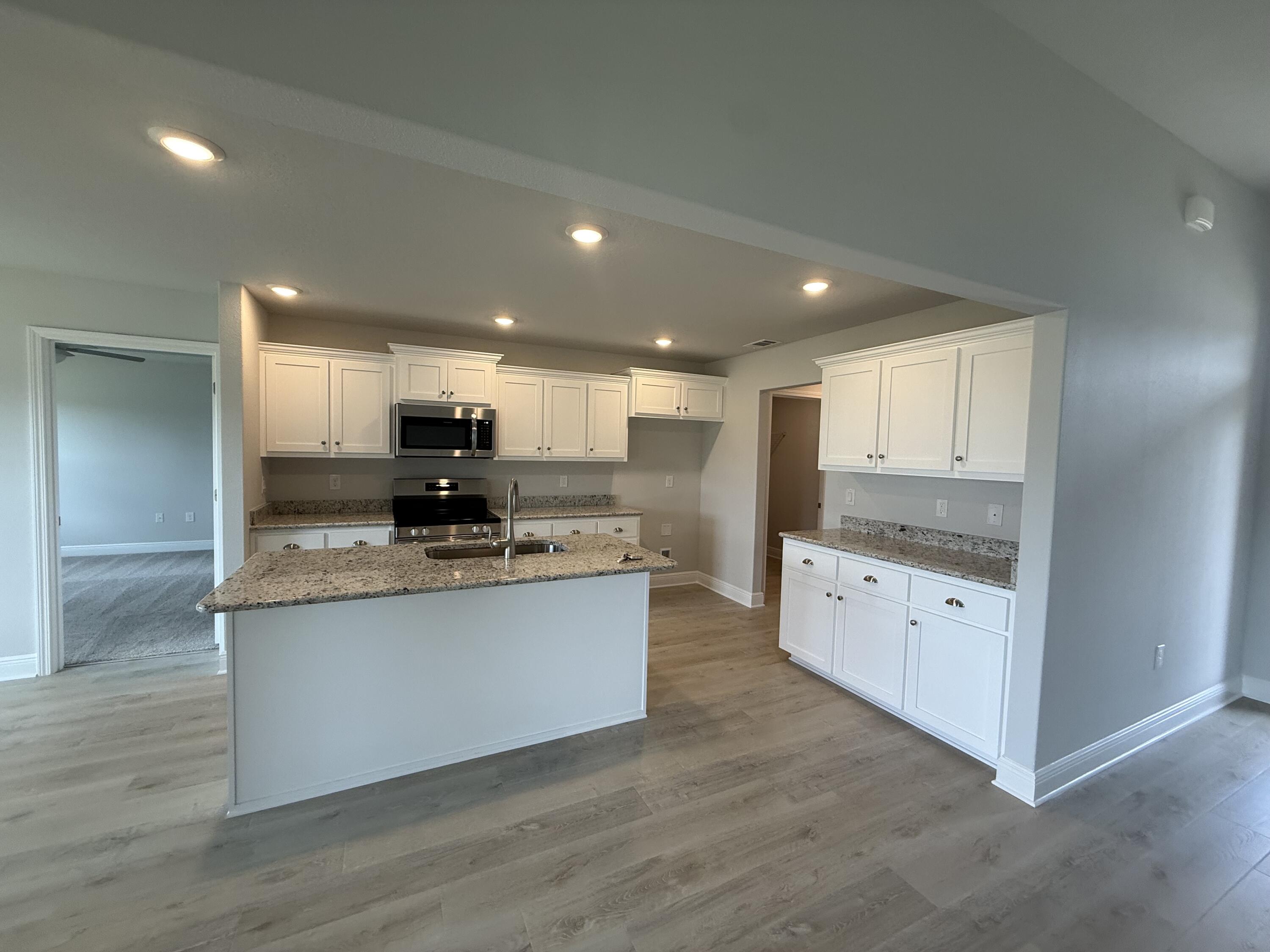 6002 Crocket Cove Crestview, FL 32539 - Photo 16 of 29 a large kitchen with stainless steel appliances kitchen island granite countertop a large counter top and wooden floors