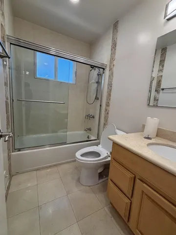 a bathroom with a granite countertop bathtub sink vanity mirror and toilet