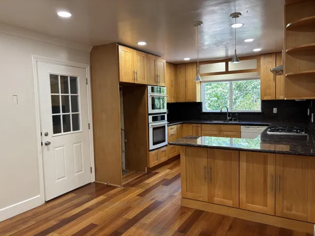 a kitchen with stainless steel appliances kitchen island granite countertop a refrigerator and a stove top oven