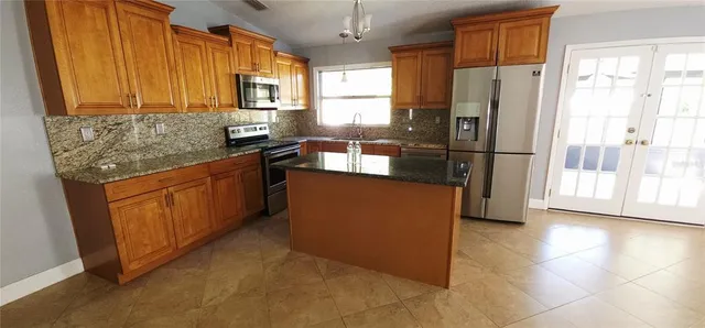 a kitchen with stainless steel appliances granite countertop a refrigerator a stove a sink and dishwasher
