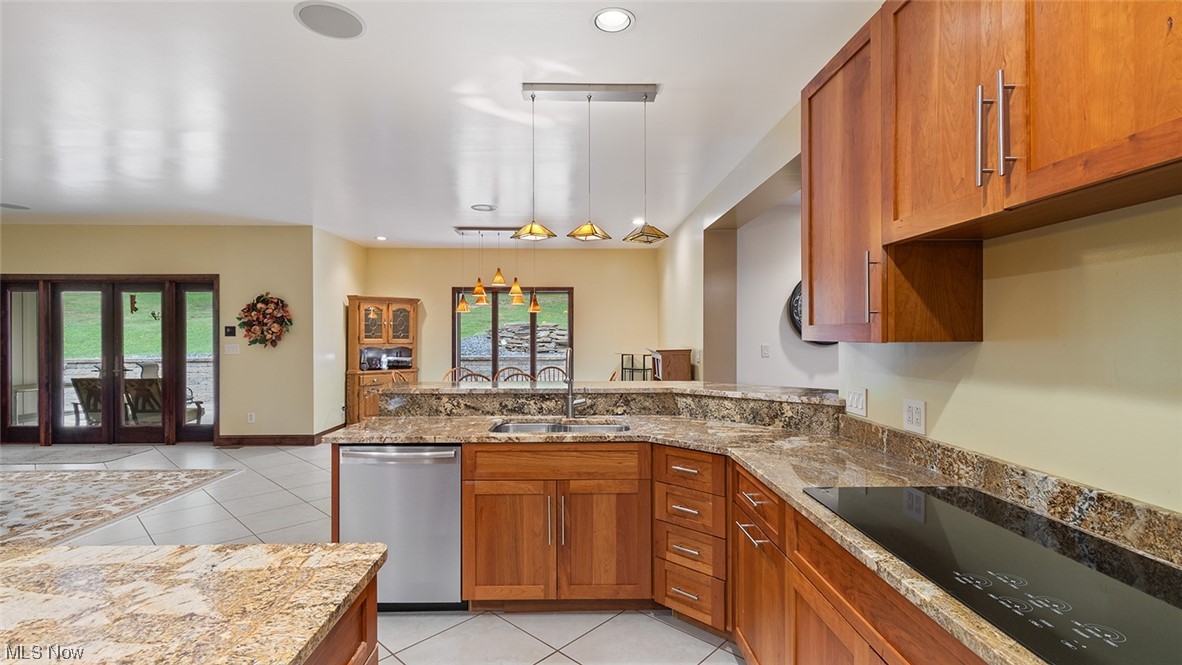 57430 Ohio Riverview Road Shadyside, OH 43947 - Photo 15 of 35 Kitchen with stone counters, decorative light fixtures, stainless steel dishwasher, brown cabinets, black electric stovetop, a healthy amount of sunlight, and light tile floors