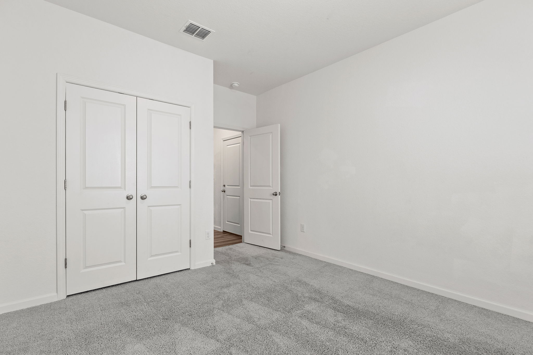 409 Line Of Fire Way Jarrell, TX 76537 - Photo 11 of 30 Neutral-toned room featuring light gray carpeting, double-door closet with panel detailing, brushed nickel hardware, white trim, and open wall space.