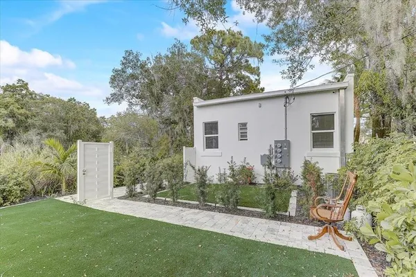 a view of a backyard with plants and large trees