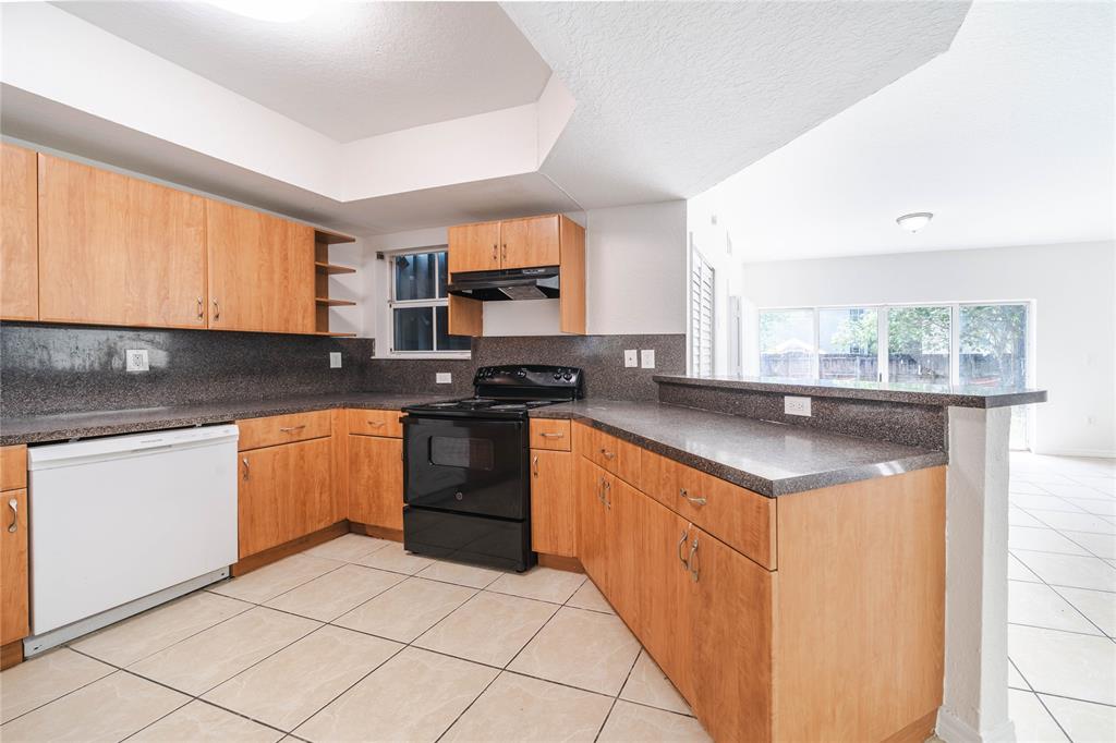 845 Southwest 6th Court Homestead, FL 33034 - Photo 10 of 30 a kitchen with stainless steel appliances granite countertop a stove a sink and a microwave