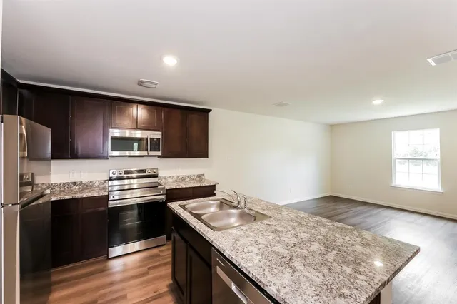 a kitchen with a sink dishwasher a refrigerator and wooden cabinets with wooden floor