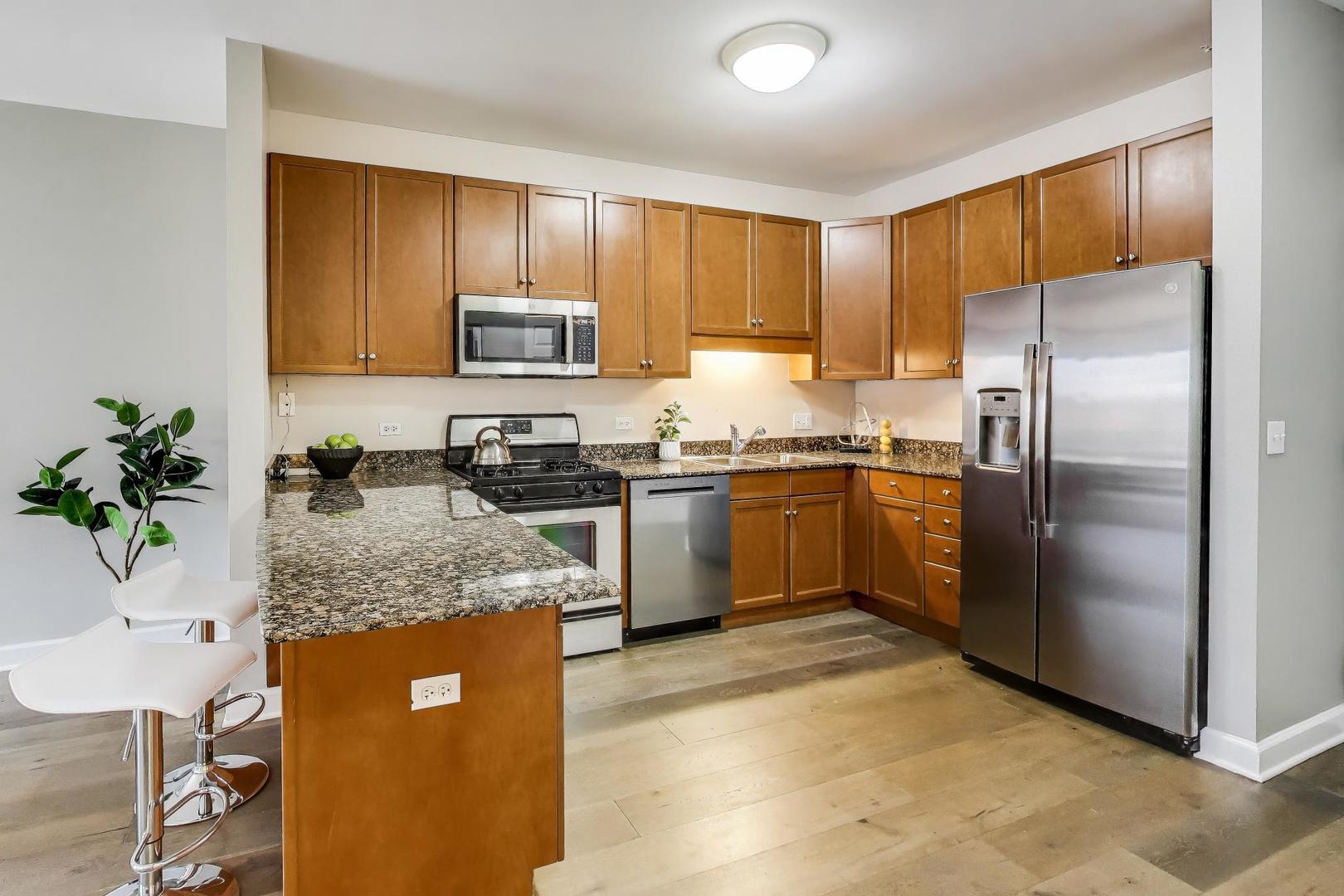 1155 South State Street, Unit C404 Chicago, IL 60605 - Photo 6 of 18 a kitchen with stainless steel appliances granite countertop a stove a sink dishwasher a refrigerator and a microwave