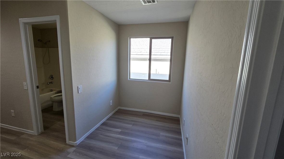 2737 Rimbaud Street Henderson, NV 89044 - Photo 34 of 49 Unfurnished bedroom with a textured wall, baseboards, dark wood-style floors, and visible vents