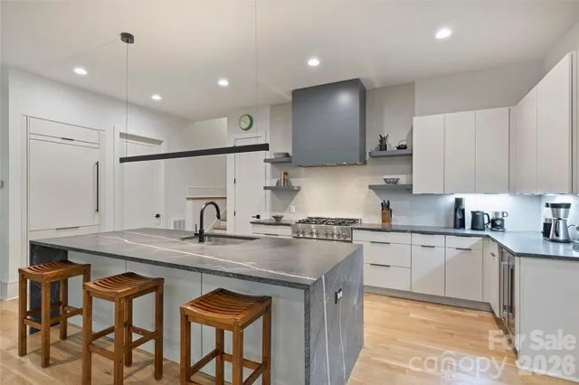 a kitchen with stainless steel appliances granite countertop a sink a stove a refrigerator island and chairs