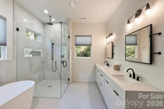 a bathroom with a double vanity sink a toilet a mirror and shower