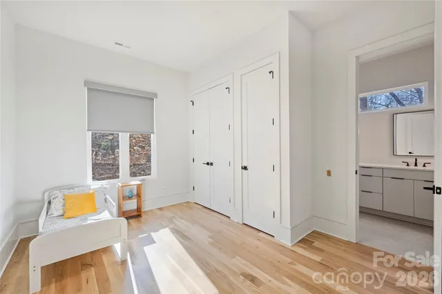 a view of a bedroom with wooden floor and a bathroom