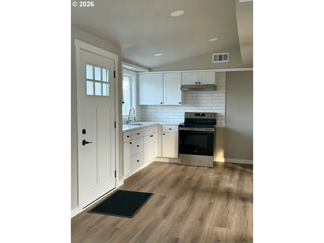 a kitchen with cabinets and wooden floor