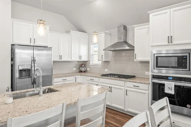 a kitchen with stainless steel appliances granite countertop a stove a sink and a refrigerator