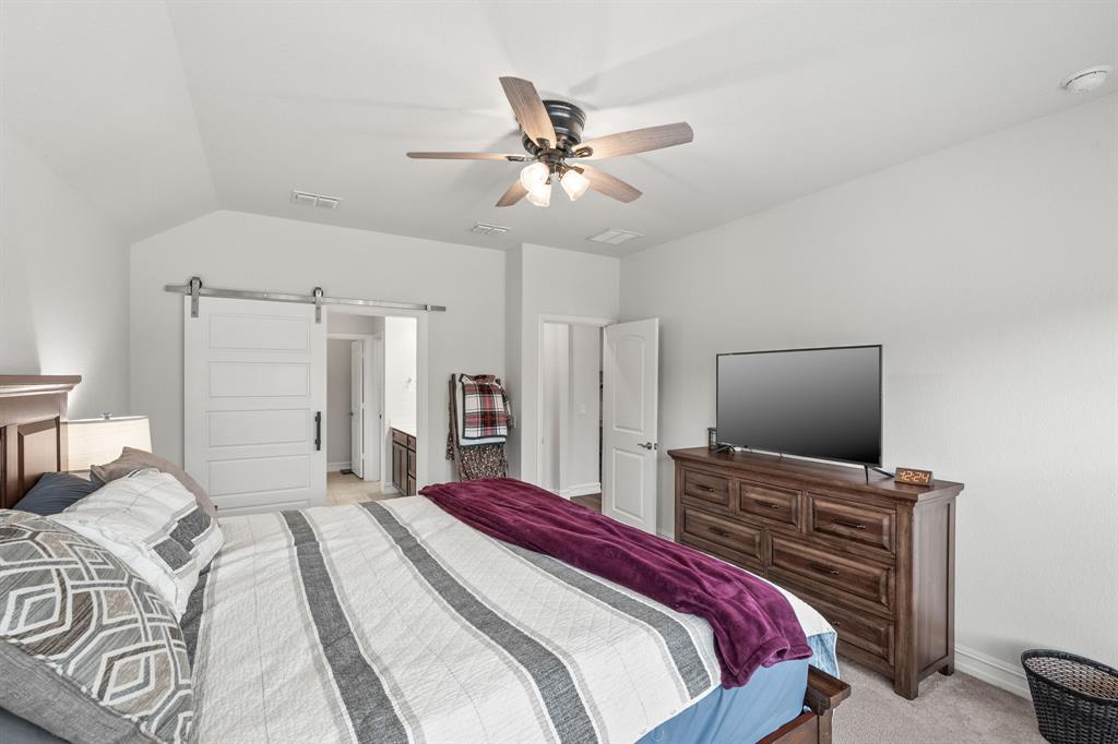 2920 Arlo Road Aubrey, TX 76227 - Photo 19 of 31 a bedroom with a bed and a flat screen tv