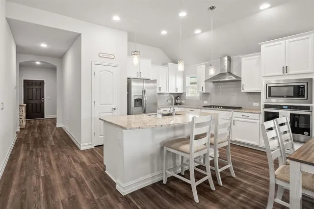a kitchen with stainless steel appliances kitchen island granite countertop a table chairs sink and cabinets