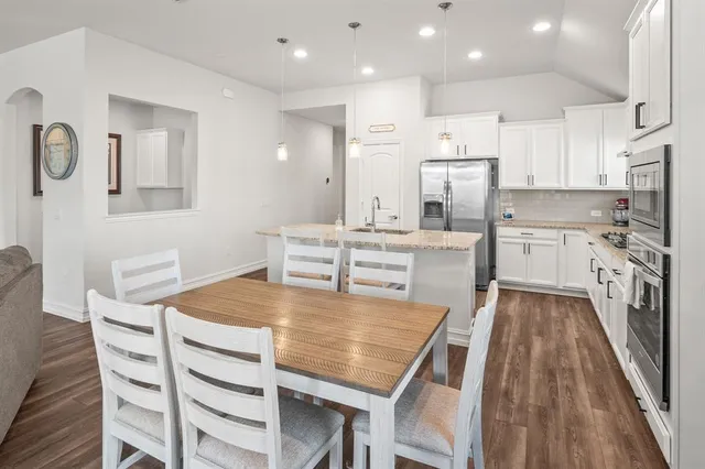 a kitchen with stainless steel appliances granite countertop a stove a sink dishwasher and a refrigerator with wooden floor