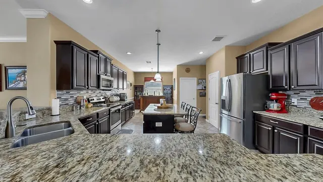 a kitchen with stainless steel appliances granite countertop a sink a stove and a refrigerator