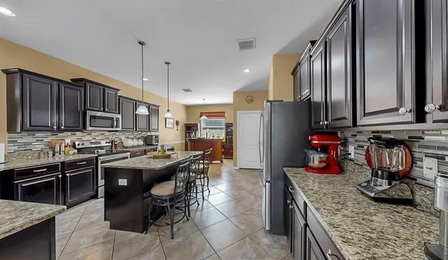 a kitchen with stainless steel appliances granite countertop a sink a stove and a wooden cabinets