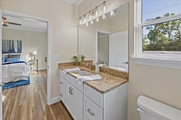 a spacious bathroom with a granite countertop sink a mirror and a toilet