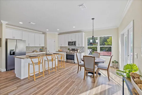 a kitchen with stainless steel appliances granite countertop a stove top oven a sink dishwasher a dining table and chairs with wooden floor