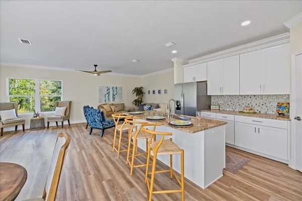 a open dining room with stainless steel appliances granite countertop a stove and white cabinets