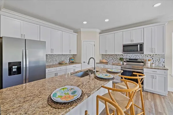 a kitchen with stainless steel appliances granite countertop a stove a sink a microwave a refrigerator and white cabinets