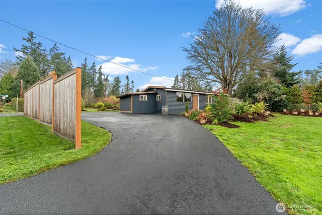 a yellow house with flower garden and wooden fence