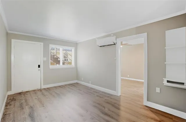 a view of an empty room with wooden floor and a window