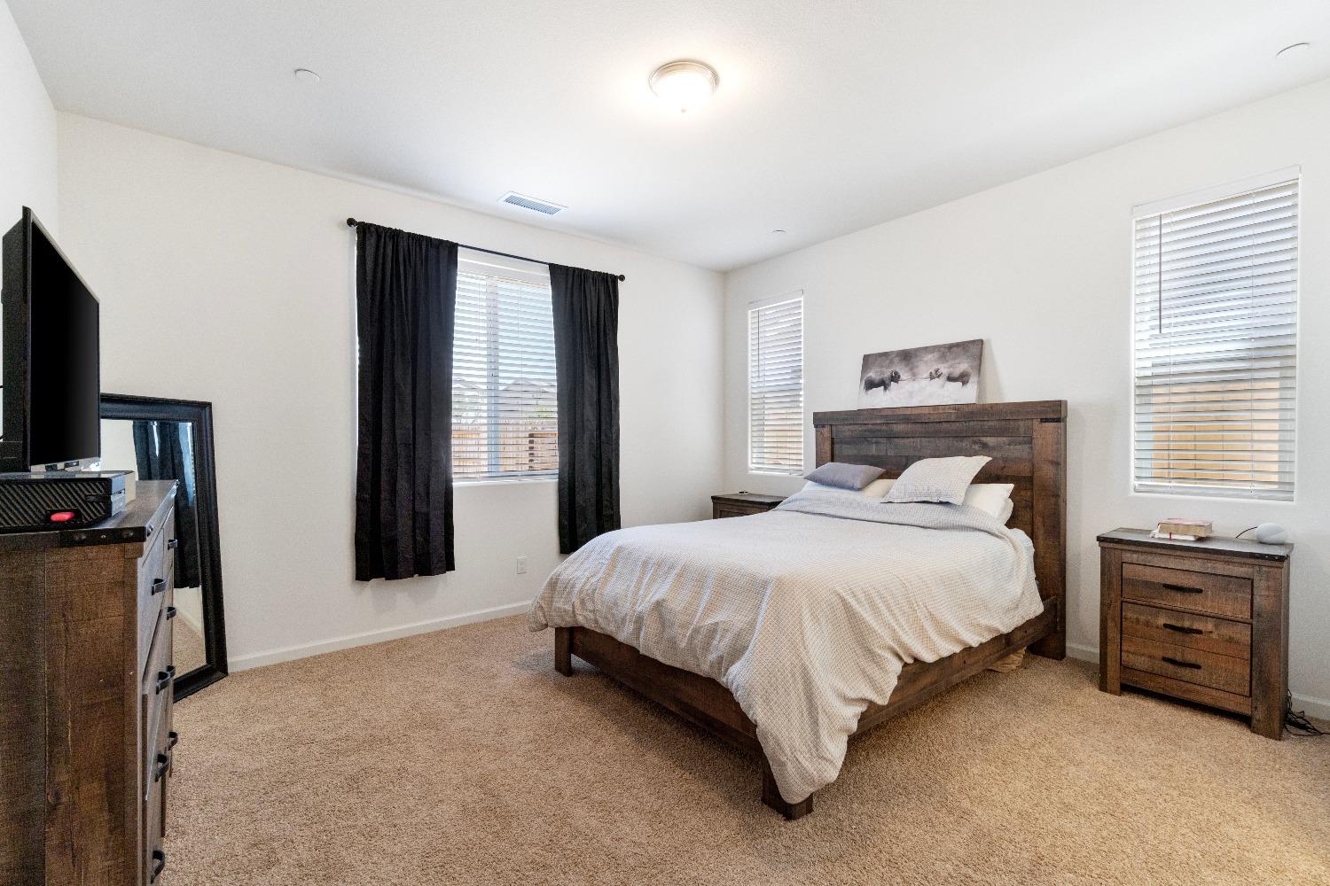 1241 Peters Road Madera, CA 93636 - Photo 27 of 37 a bedroom with a bed a mirror on dresser and a window