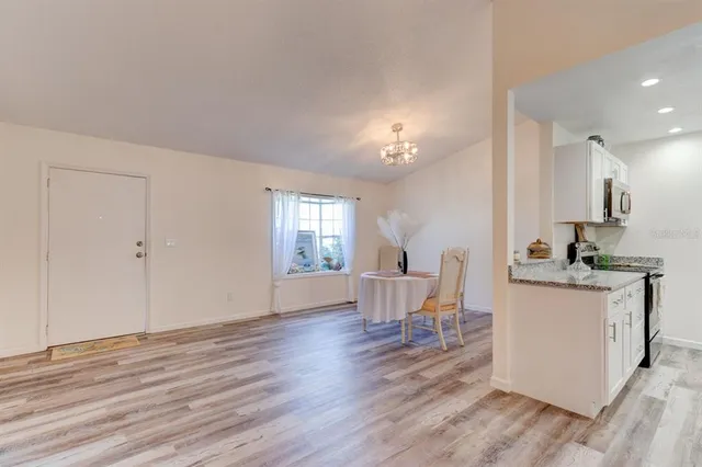 a living room with stainless steel appliances kitchen island hardwood floor and a sink