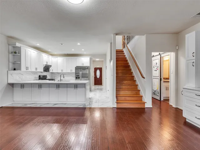 a view of open kitchen with granite countertop cabinets stove top oven and sink