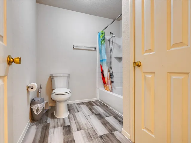 a view of an empty room with a window and a kitchen view