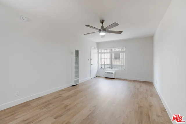 an empty room with wooden floor fan and windows