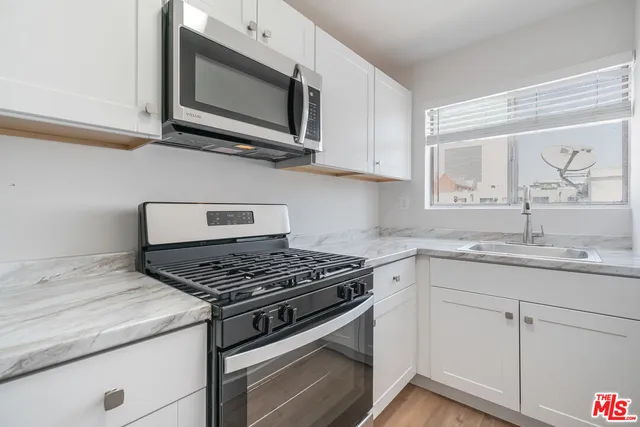 a kitchen with stainless steel appliances granite countertop white cabinets a stove top oven and dishwasher