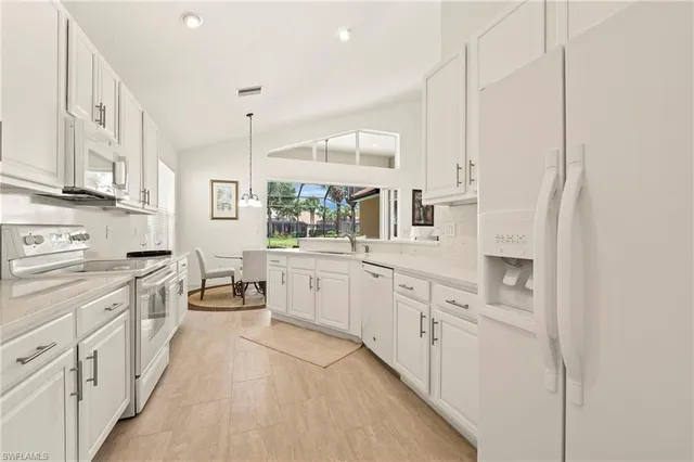 a large white kitchen with stainless steel appliances and white cabinets