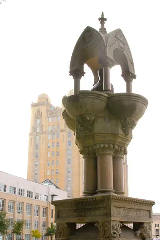 a view of a tall building next to a big yard and large trees