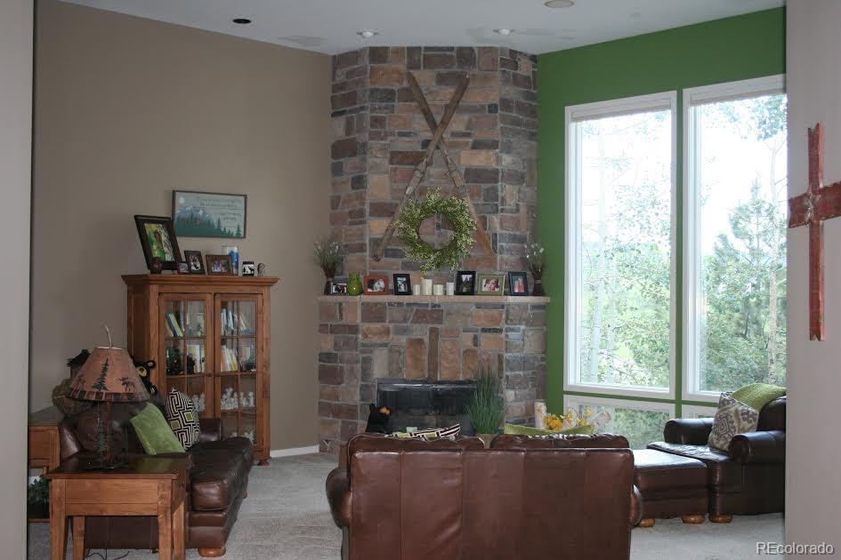 955 Castle Ridge Road Golden, CO 80401 - Photo 3 of 27 a living room with furniture a fireplace and a floor to ceiling window