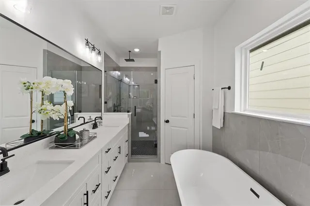 a spacious bathroom with double vanity sinks a large mirror and a shower