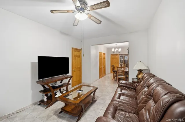 a living room with furniture a flat screen tv and a ceiling fan