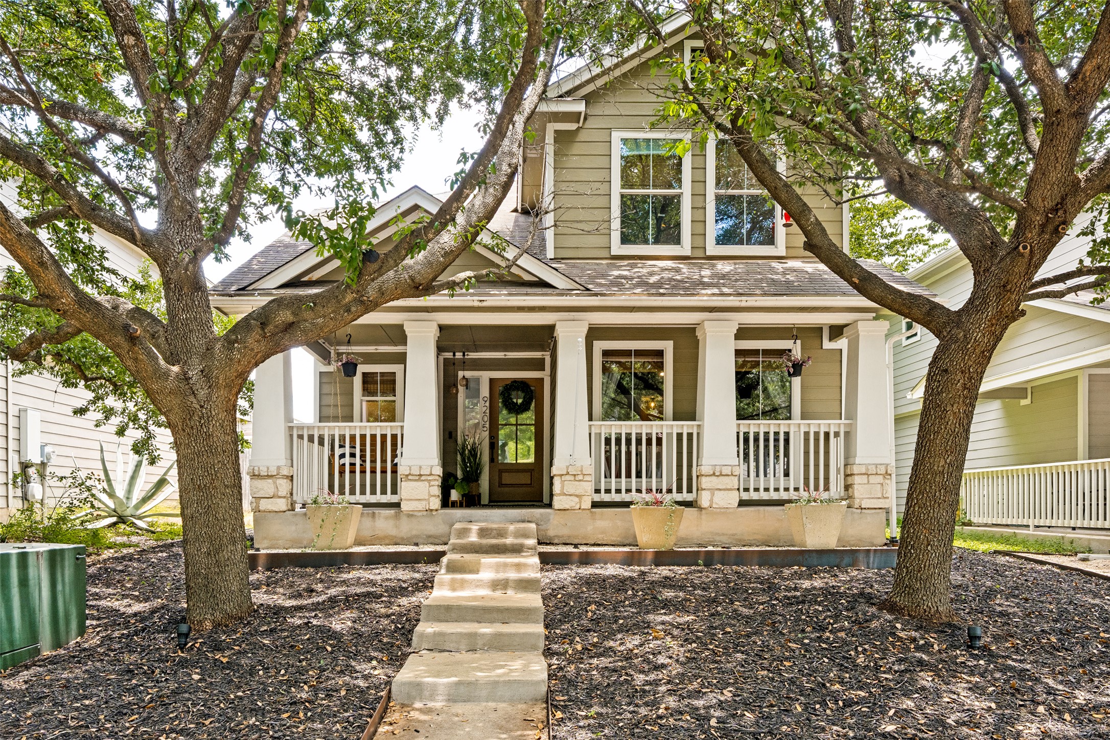 9205 Rowlands Sayle Road Austin, TX 78744 - Photo 3 of 25 A welcoming front porch with white columns and railing graces this two-story home, nestled between mature trees.