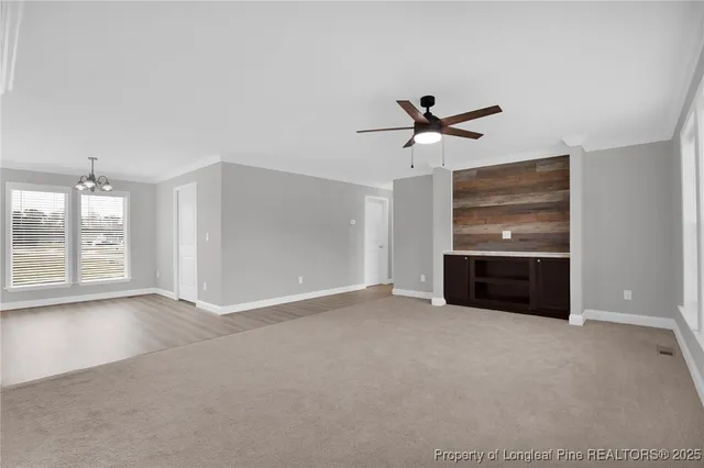 an empty room with windows and ceiling fan