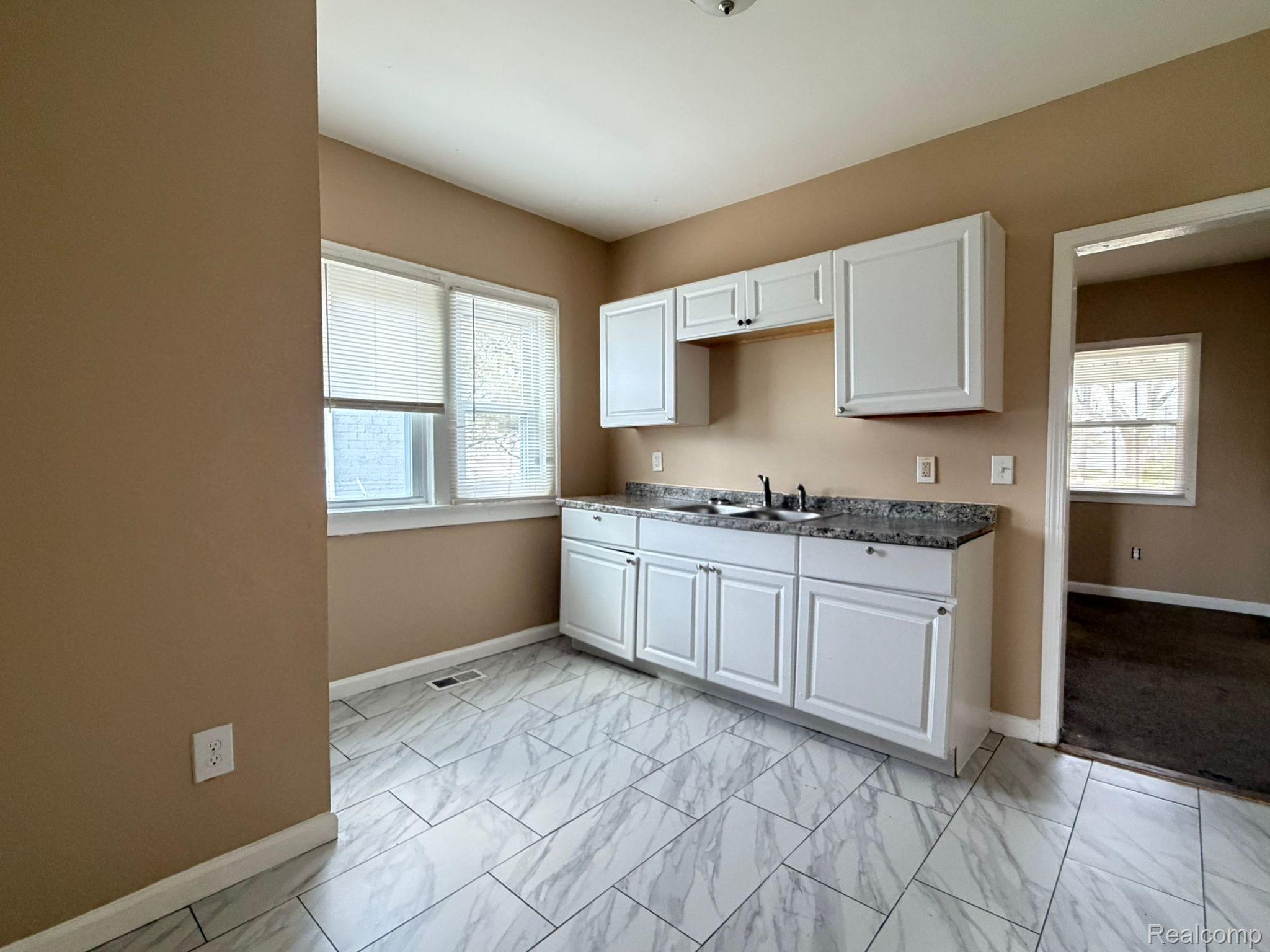 15935 Normandy Street Detroit, MI 48238 - Photo 23 of 28 Kitchen space featuring white cabinetry, a double basin sink, and stone-finish countertops