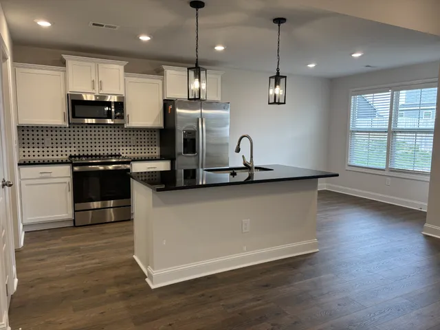 a kitchen with stainless steel appliances granite countertop a sink a stove a refrigerator and wooden floor