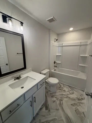 a bathroom with a sink vanity granite toilet and shower