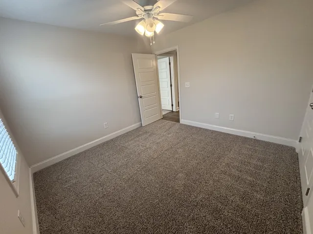 an empty room with a chandelier fan and windows