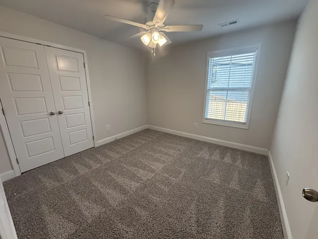 an empty room with windows and fan